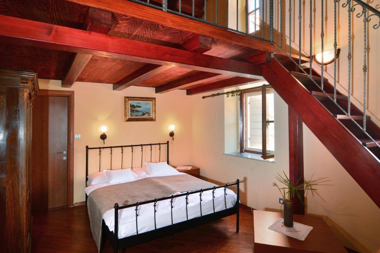Villa Nora Hvar: loft room with a wooden staircase and an iron bed
